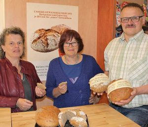 Bei der Verkostung überzeugen sich Daniela Müller (links) und Ilse Wolf von der würzigen Schmackhaftigkeit der Gewandhauskruste. Robert Müller zeigt die beiden Brotlaibe.